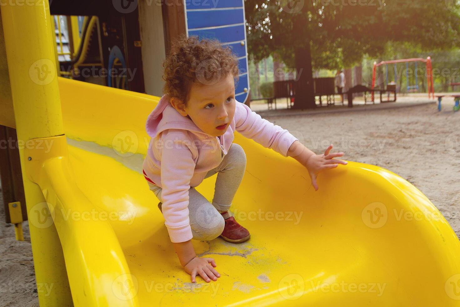 A small little child with curly hair on the playground photo