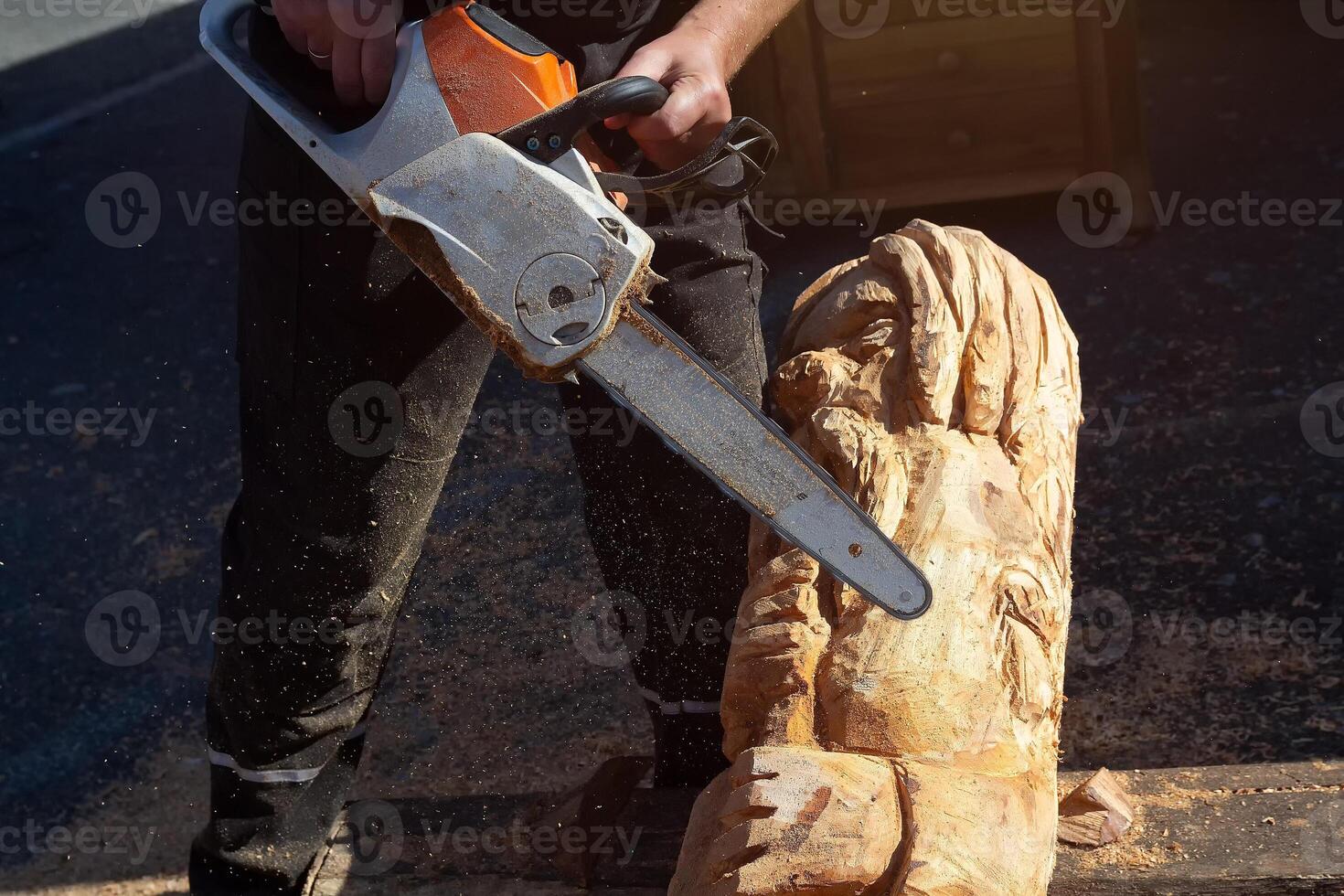 Man using chain saw to create wood carving. Industry photo