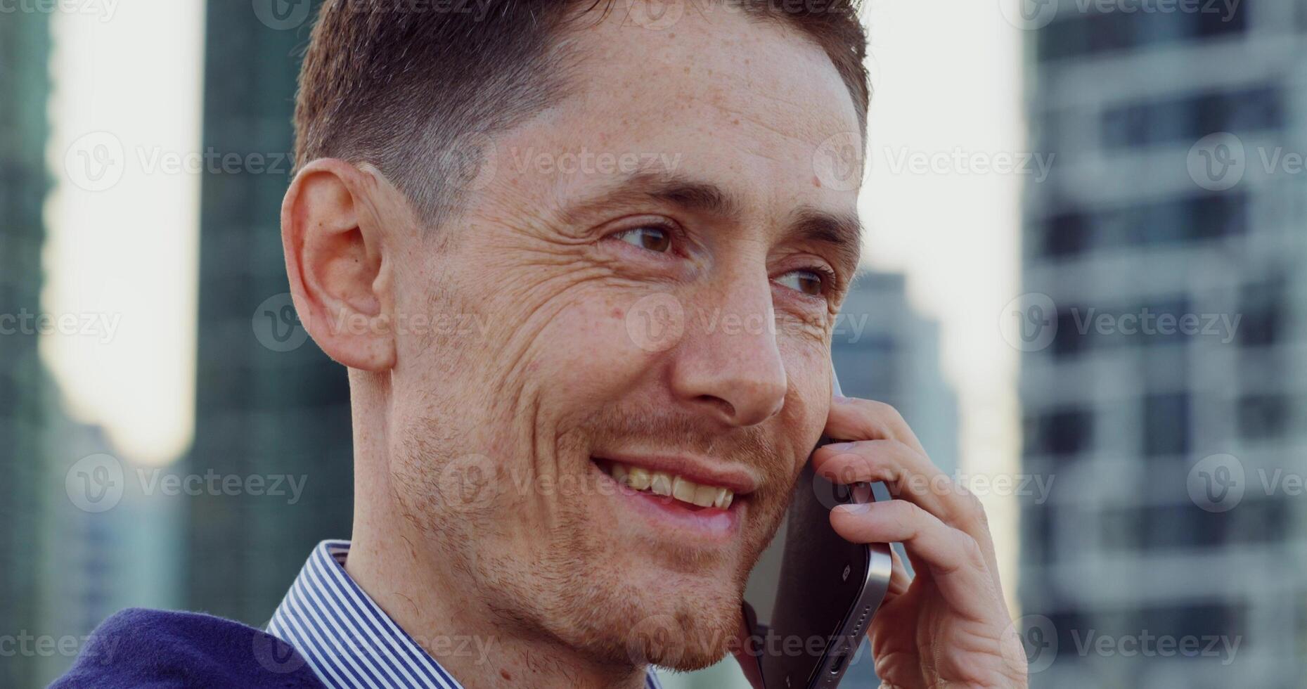 Close-up of a stylish man's face as he talks on a mobile phone while standing on a cstreet photo