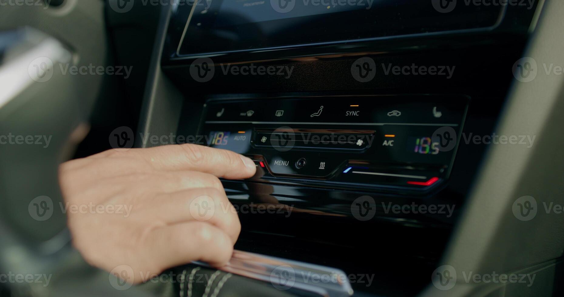 A man changes the settings of the air conditioner while driving a car. Close-up of his hands, an unrecognizable person. View from the car photo