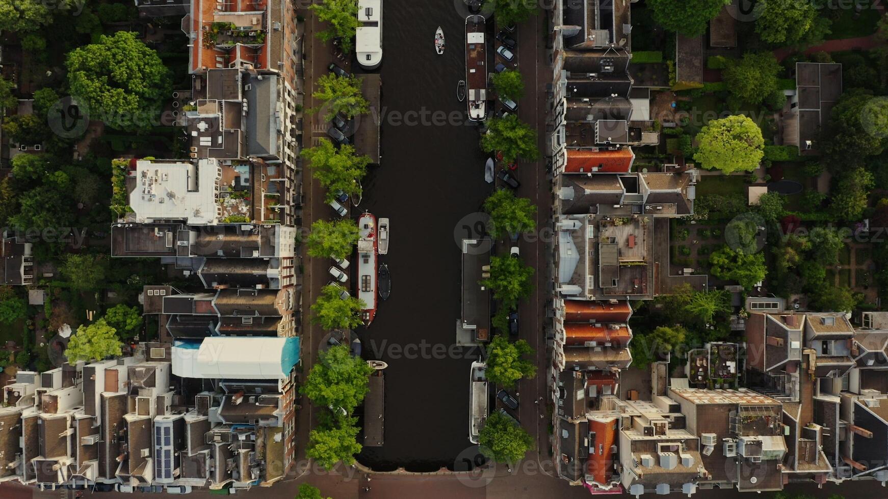 Top view of the Amsterdam canal between the streets with beautiful old traditional houses. Ships moored along the embankment, drone . Amsterdam, Netherlands - streets photo