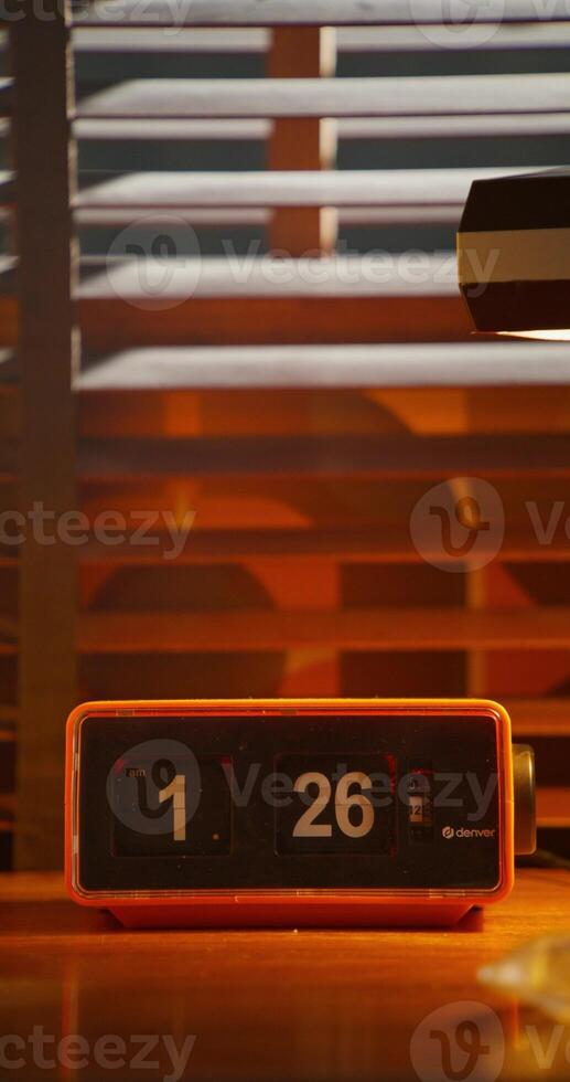 A digital clock stands next to a monitor. A desktop in a retro office photo