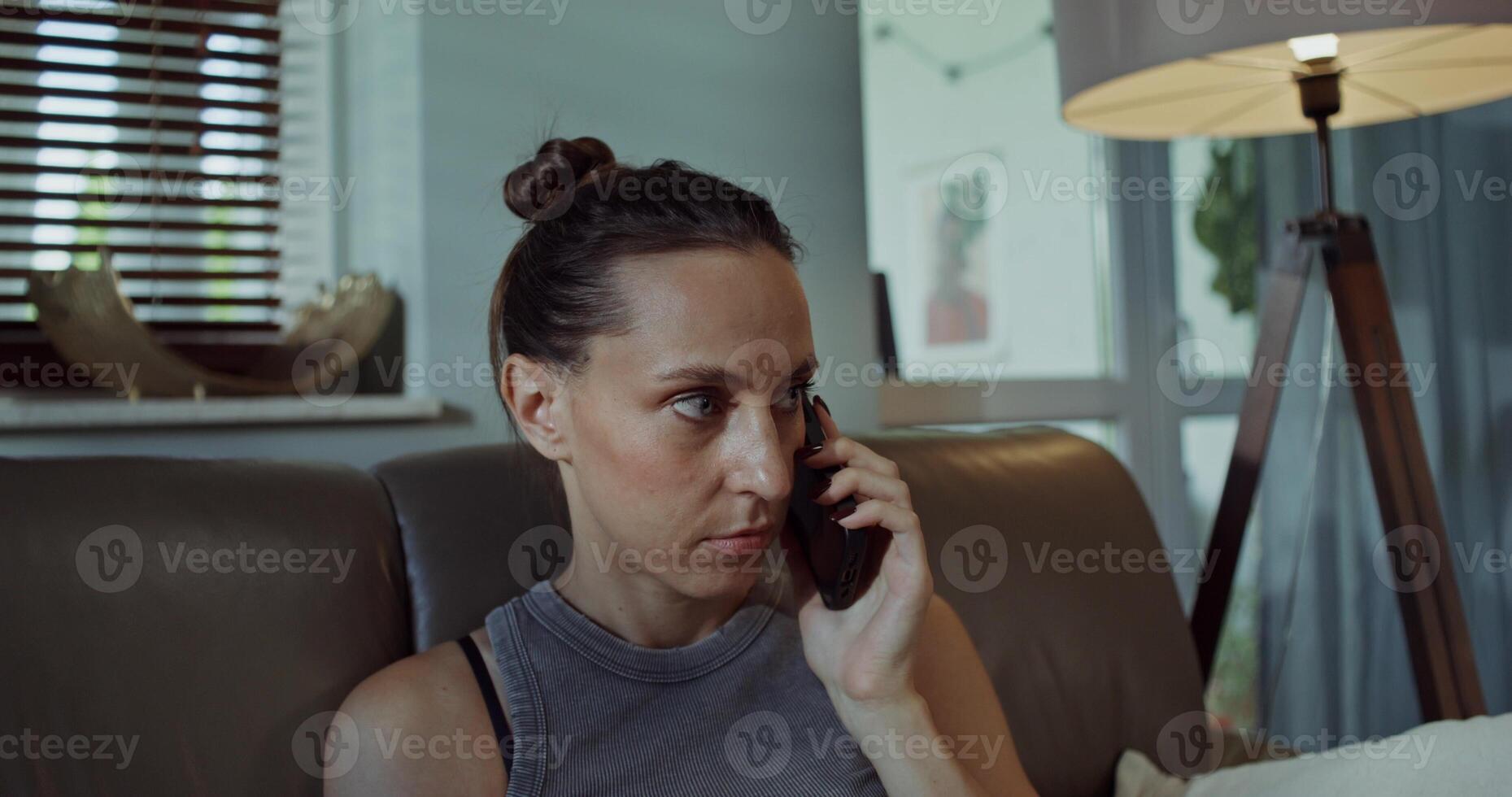 A woman is talking on a mobile phone while sitting on the couch at home. photo