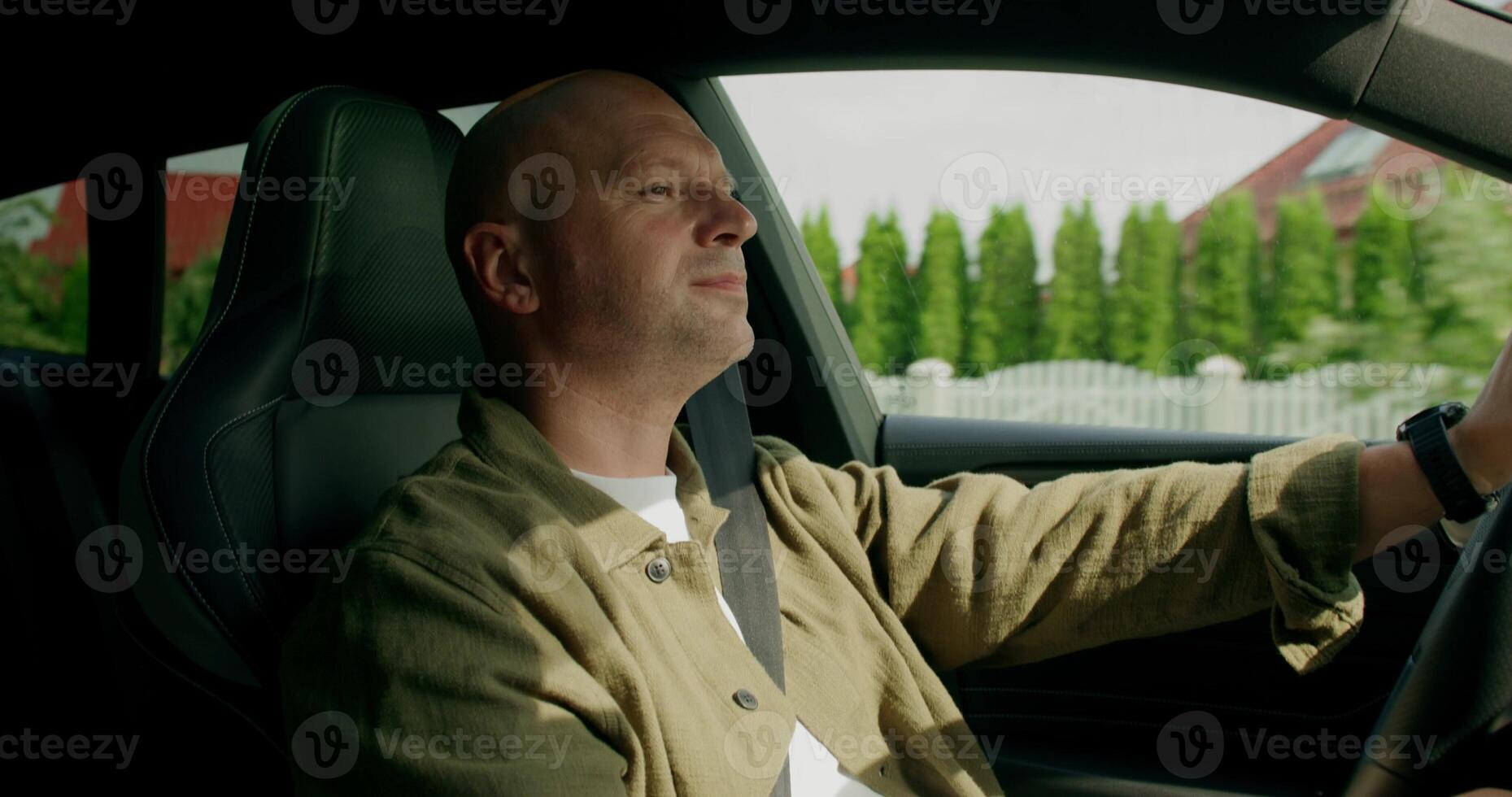 A man drinks from a bottle while driving a car. View from the car interior. Warm summer day photo