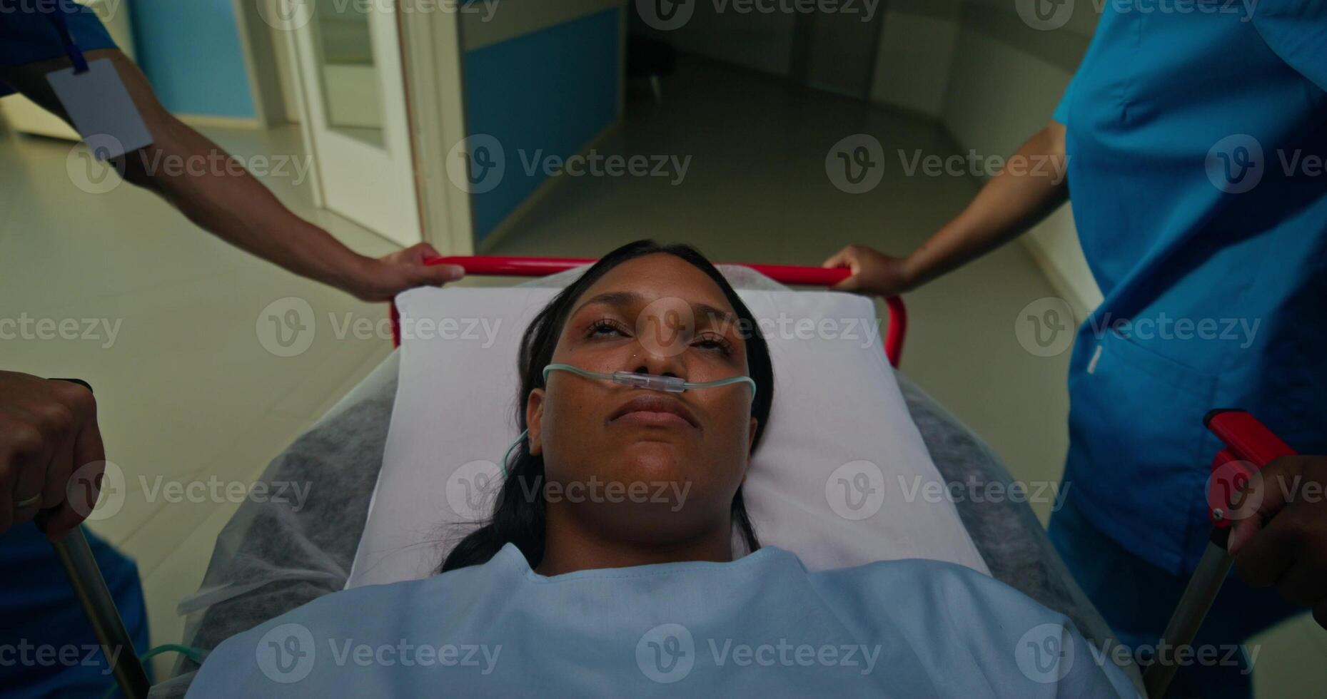 A woman with a breathing tube in her nose is lying on a gurney. photo