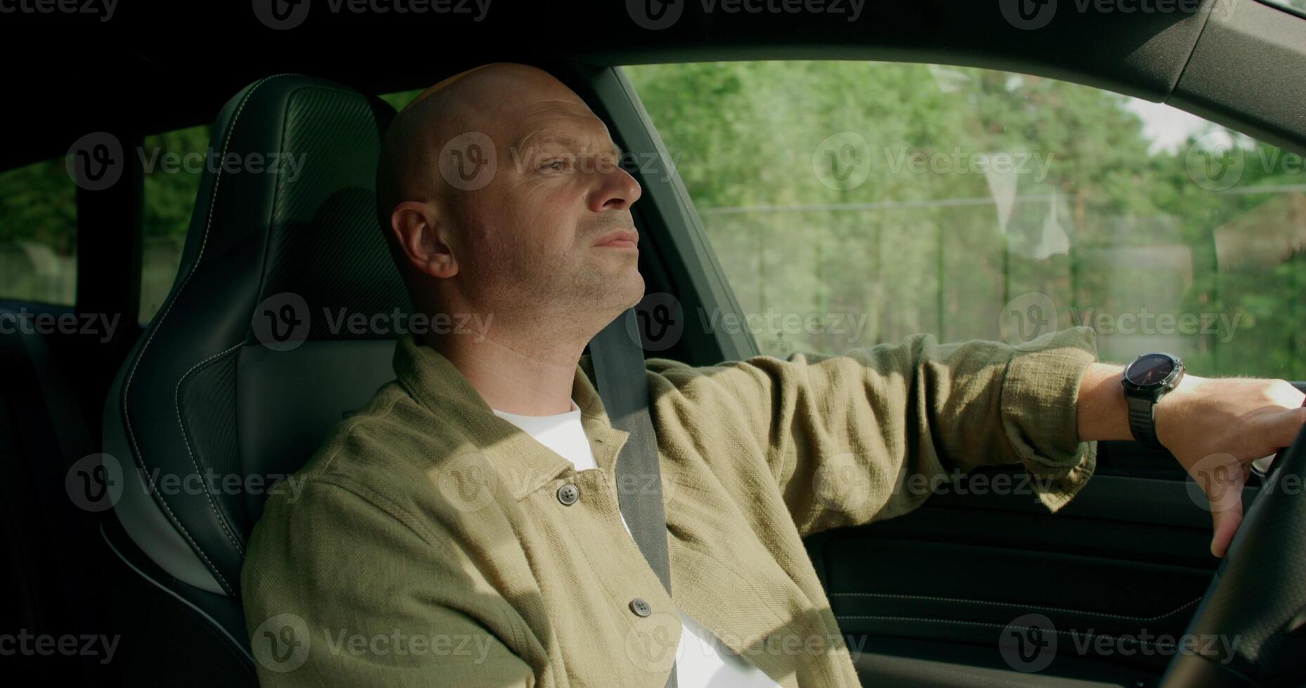 A man drinks from a bottle while driving a car. photo