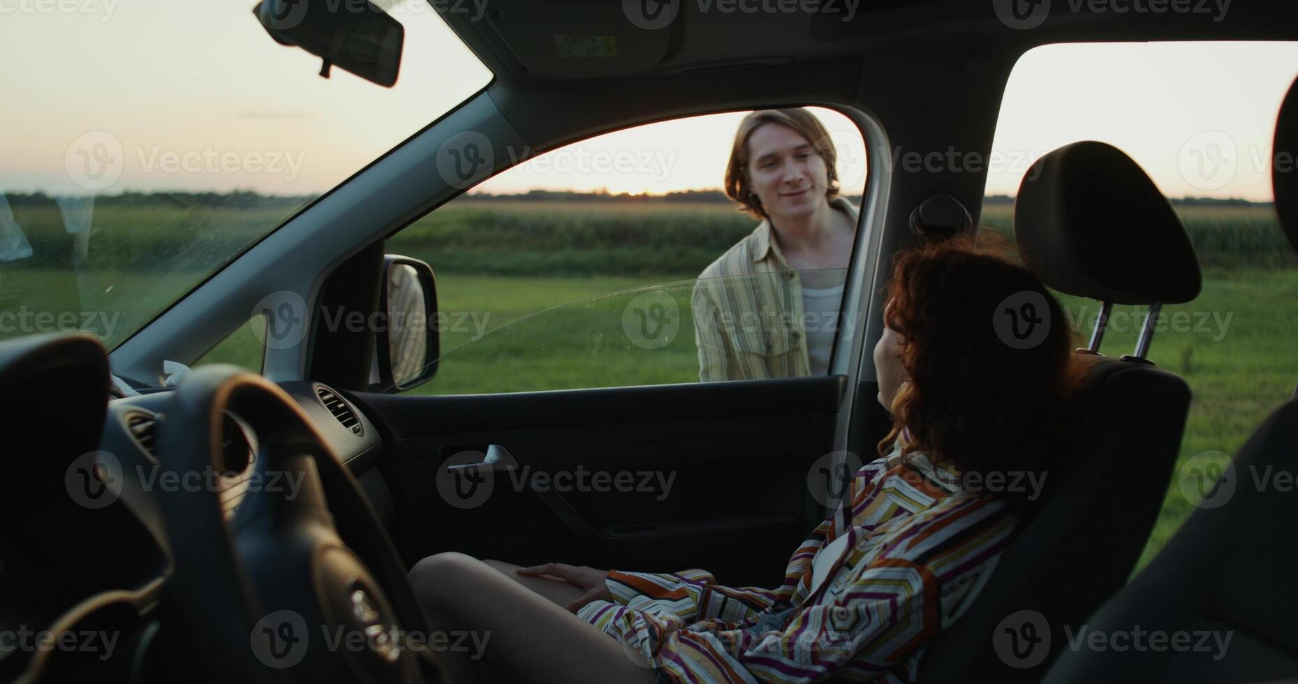 A man and a woman run from a car to a field at sunset. They're holding hands. photo