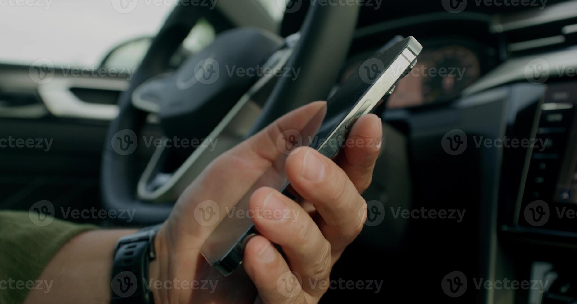 A man connects a mobile phone with a cable to a car while sitting in the driver's seat. Close-up photo
