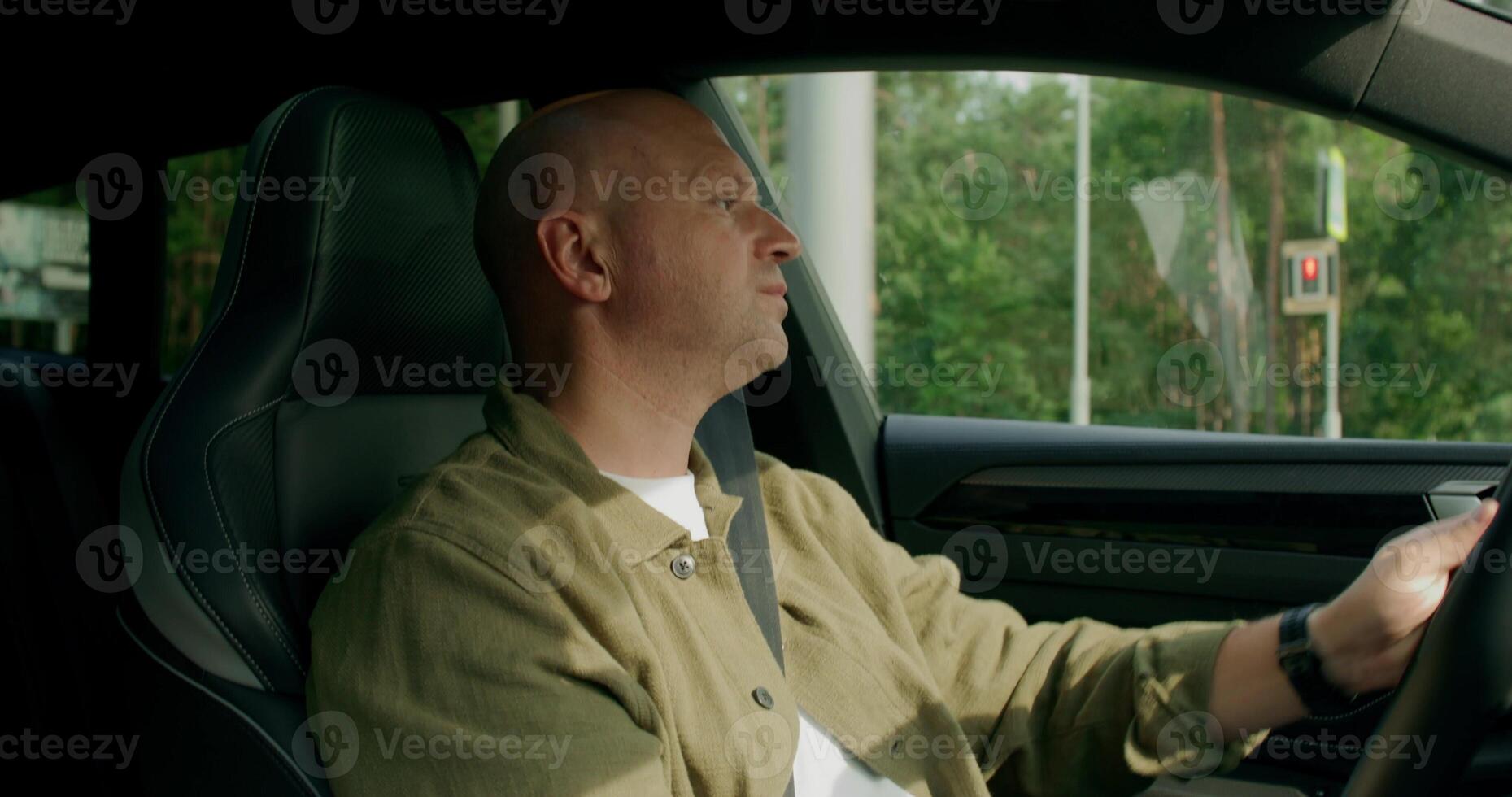 A man wearing a seat belt drives a car with a calm look. View from the car interior. photo