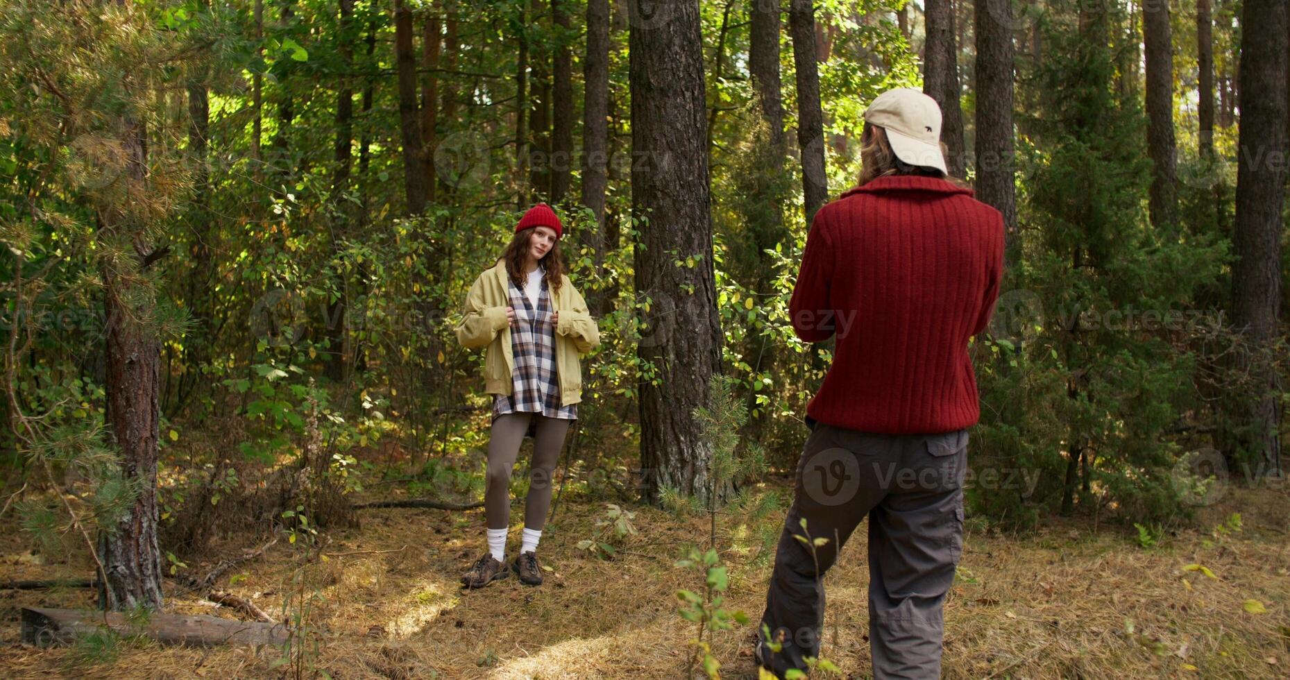 A man takes pictures of a woman in the forest with a camera. Photo shoot in nature