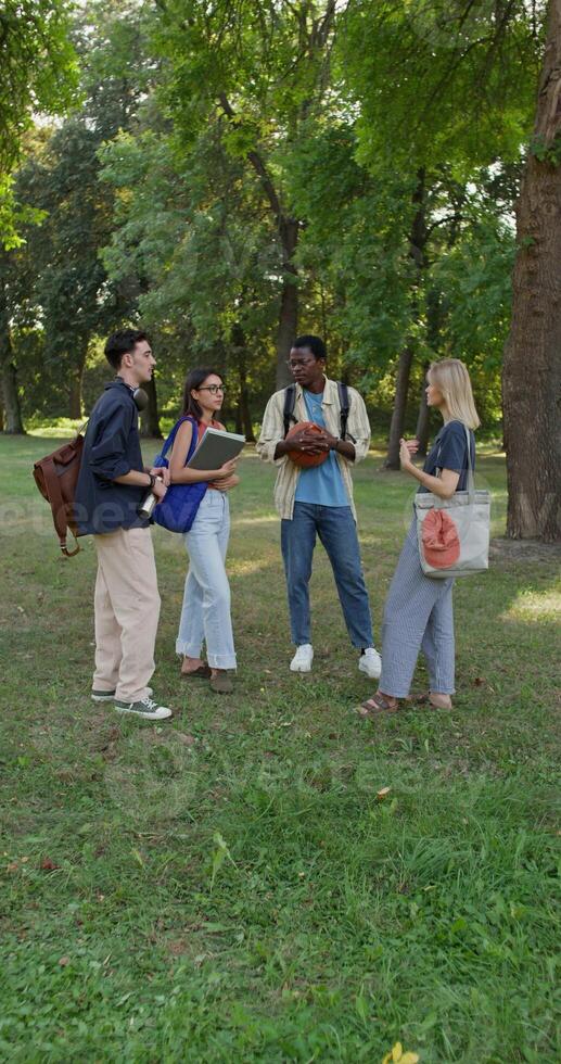 A group of students are talking and smiling while standing in a city park during recess. photo