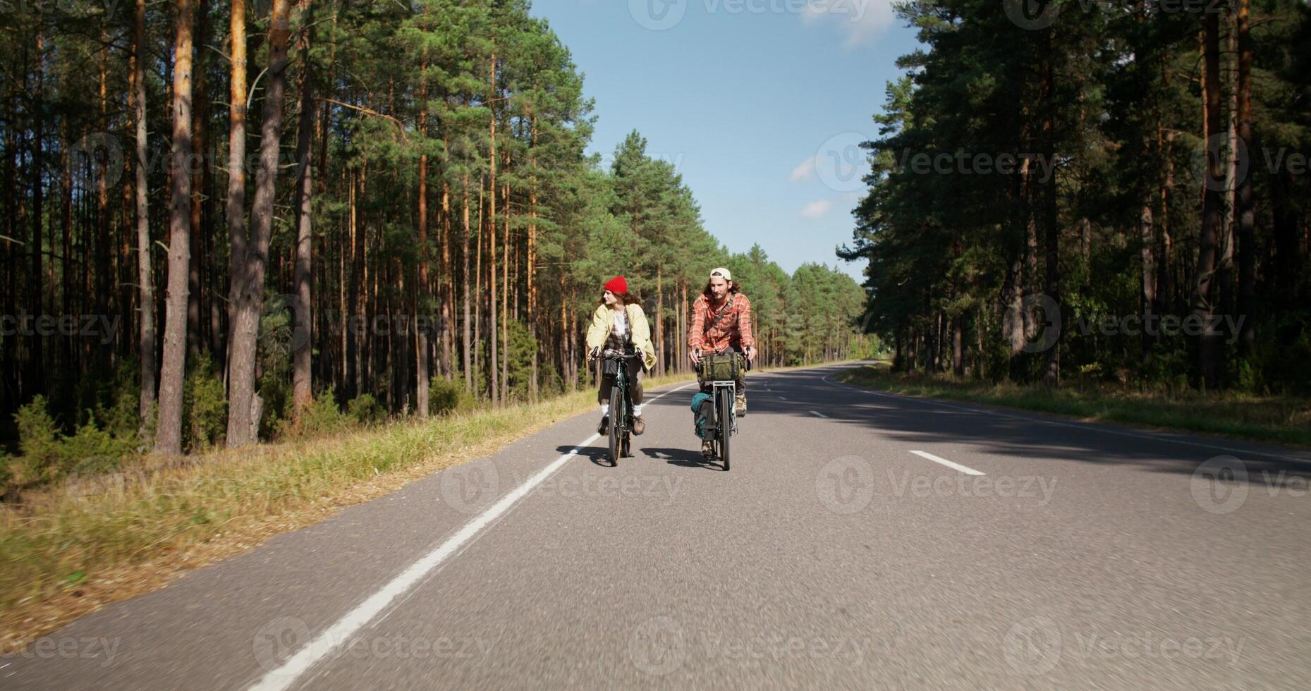 A young couple is riding a bike on a road in the middle of the forest. leisure on a sunny day photo