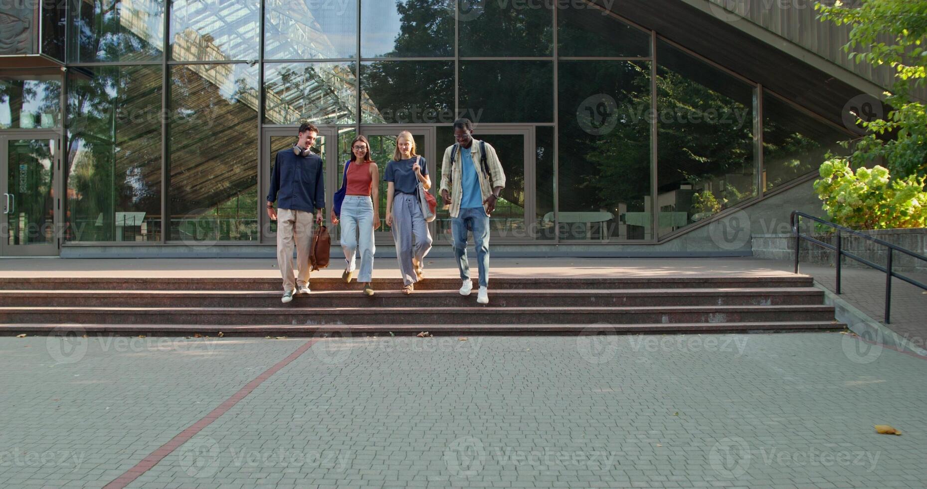 A group of young people hug and say goodbye standing near a glass building. photo