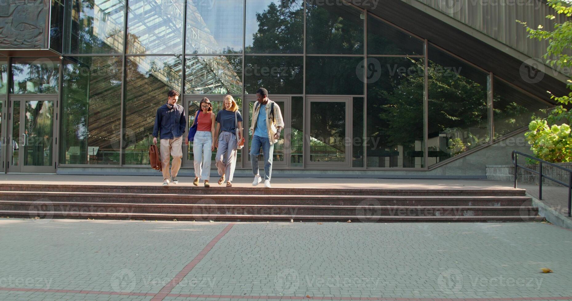 A group of students are talking and smiling as they walk away from the university. S photo
