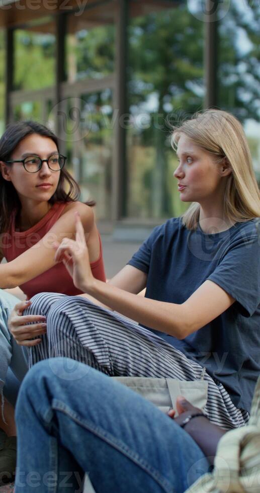 A group of people are talking while sitting on the university steps on a summer day photo