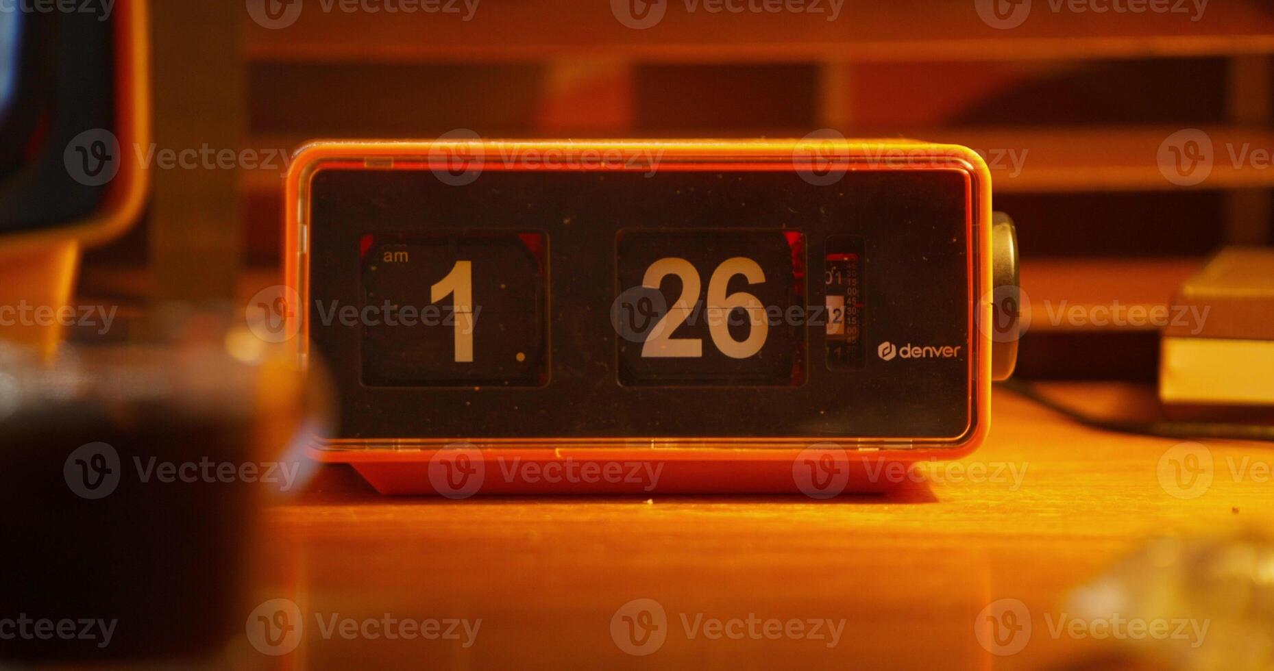 A digital clock stands next to a monitor with ripples on the screen. A desktop in office photo