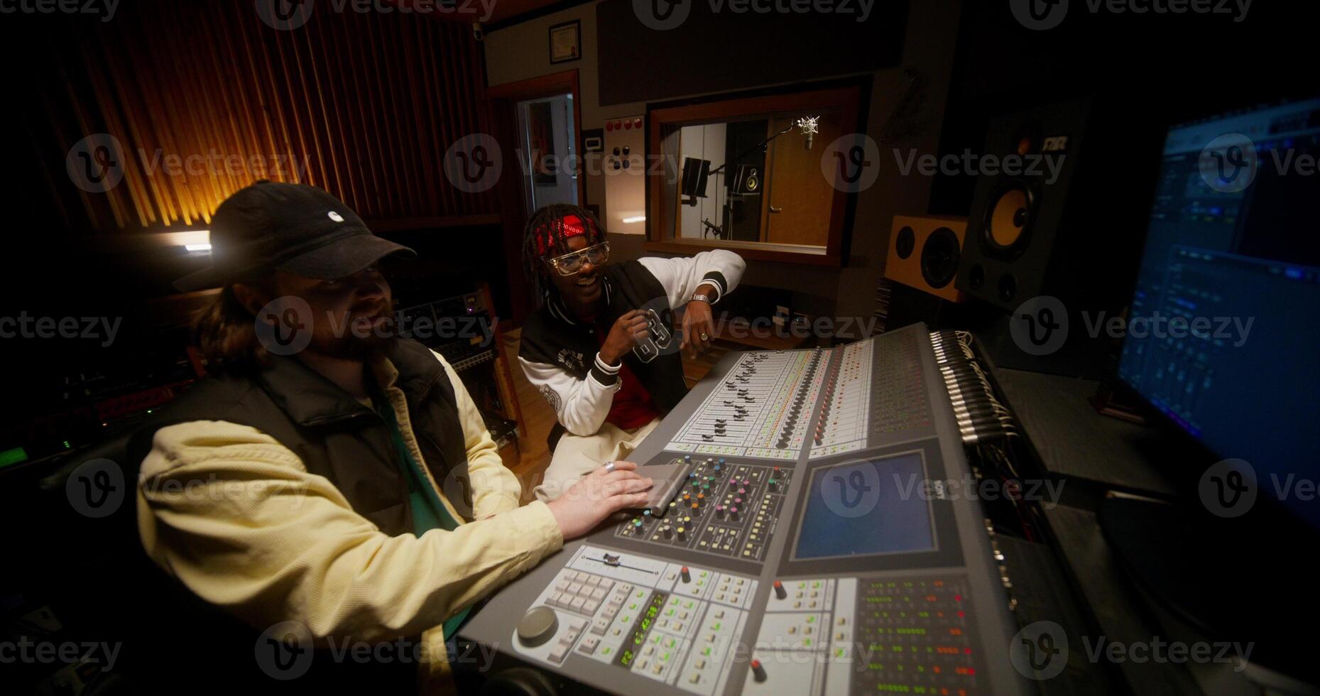 A sound engineer and a singer listen a recorded song sitting in front of an audio mixer. Working in a studio photo