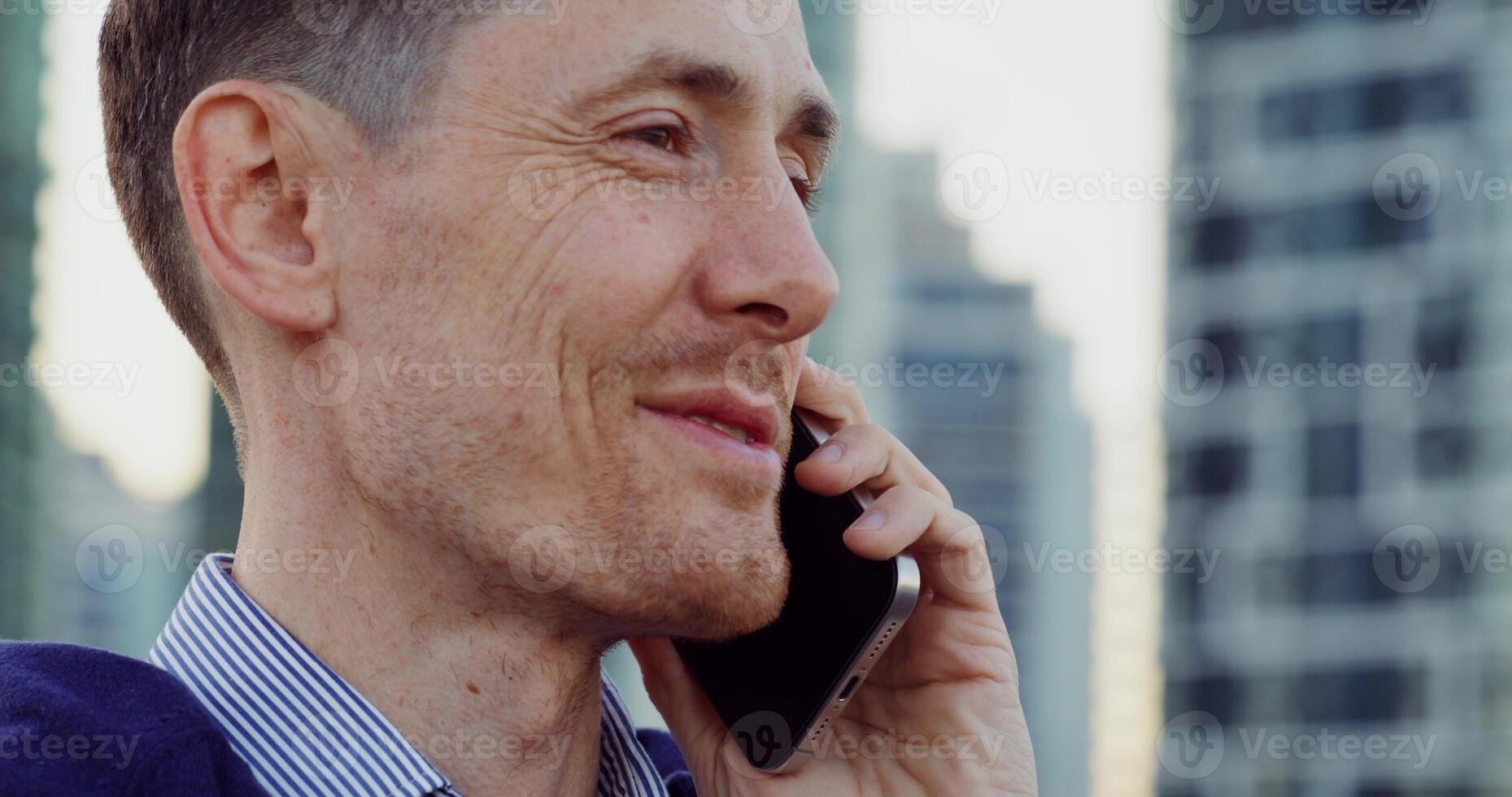 Close-up of a stylish man's face as he talks on a mobile phone while standing on a city street photo