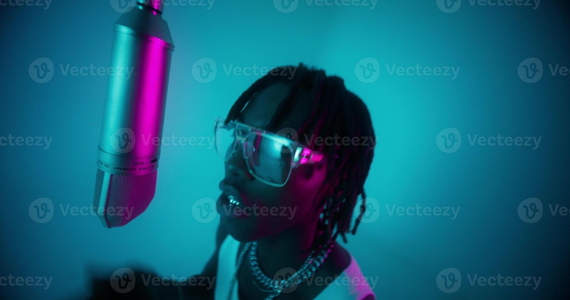 An African-American man with dreadlocks sings into a microphone. photo