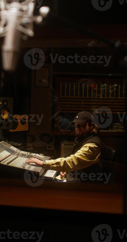 A sound engineer sits in front of an audio mixer while recording a song photo