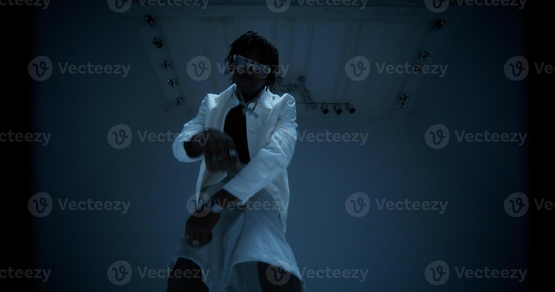 An African-American man is dancing in the studio by the light of flashes. photo