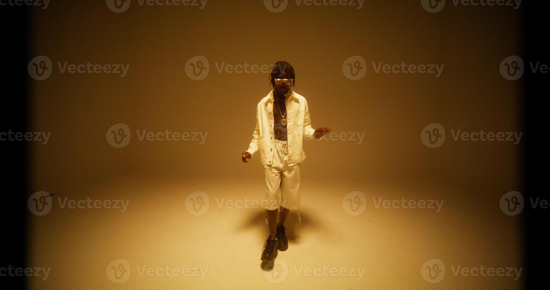 A man sings and dances in the yellow light of the studio. photo