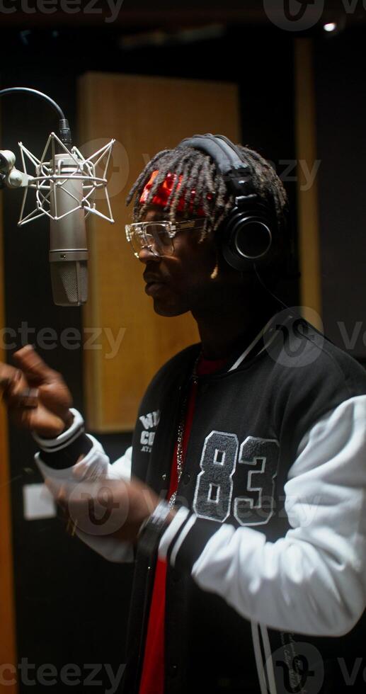 A stylish young man dances while recording rap in a recording studio photo