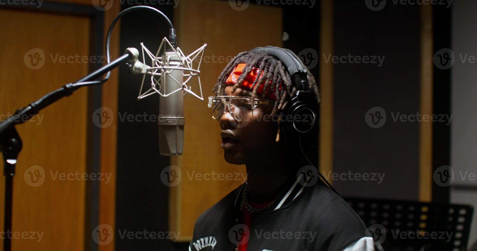 A stylish young man dances while recording rap in a studio photo