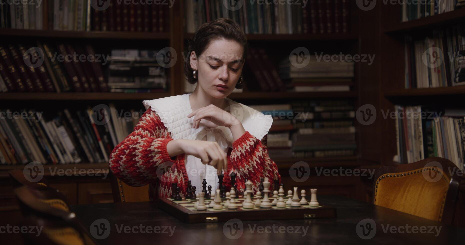 A woman of European appearance plays a chess game alone, thinking long concentratedly between moves photo