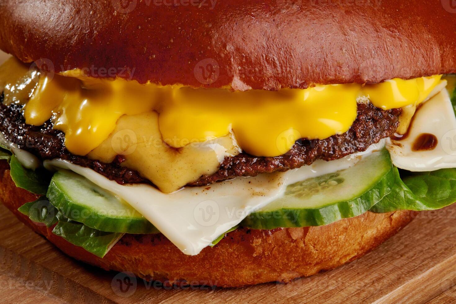 Delicious cheeseburger with melted cheddar, beef patty, and fresh cucumber on a brioche bun photo