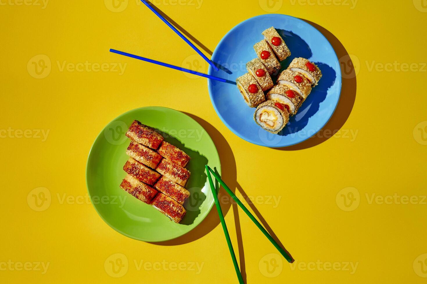 Hot sushi rolls with sesame seeds served on plates with chopsticks on yellow background photo