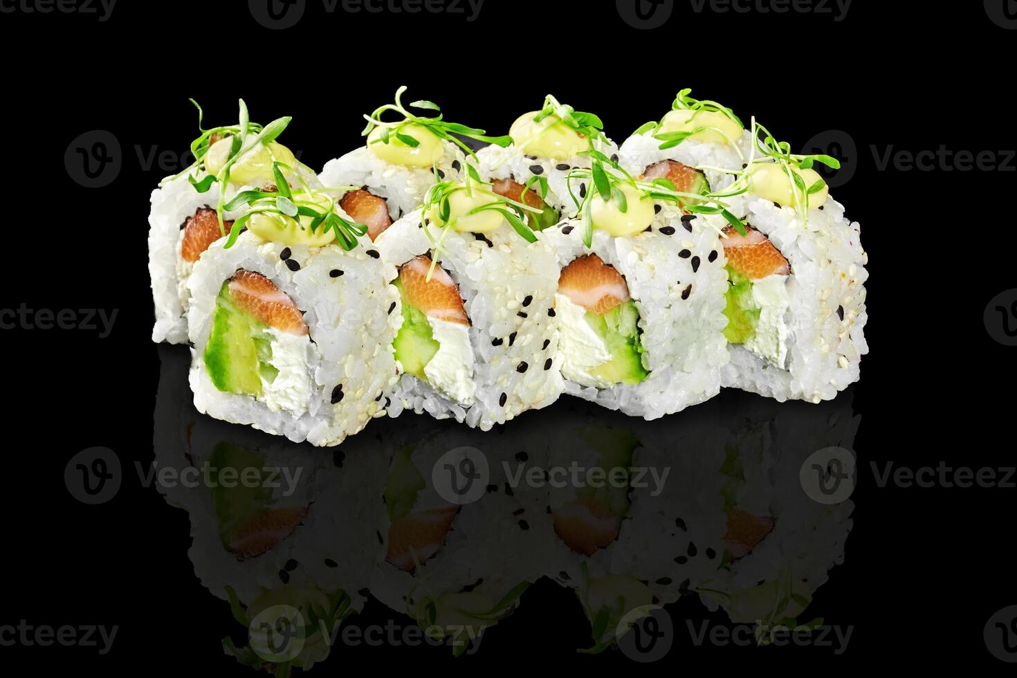 Uramaki sushi rolls with salmon, avocado, cream cheese, sesame seeds and microgreens reflecting on black background photo