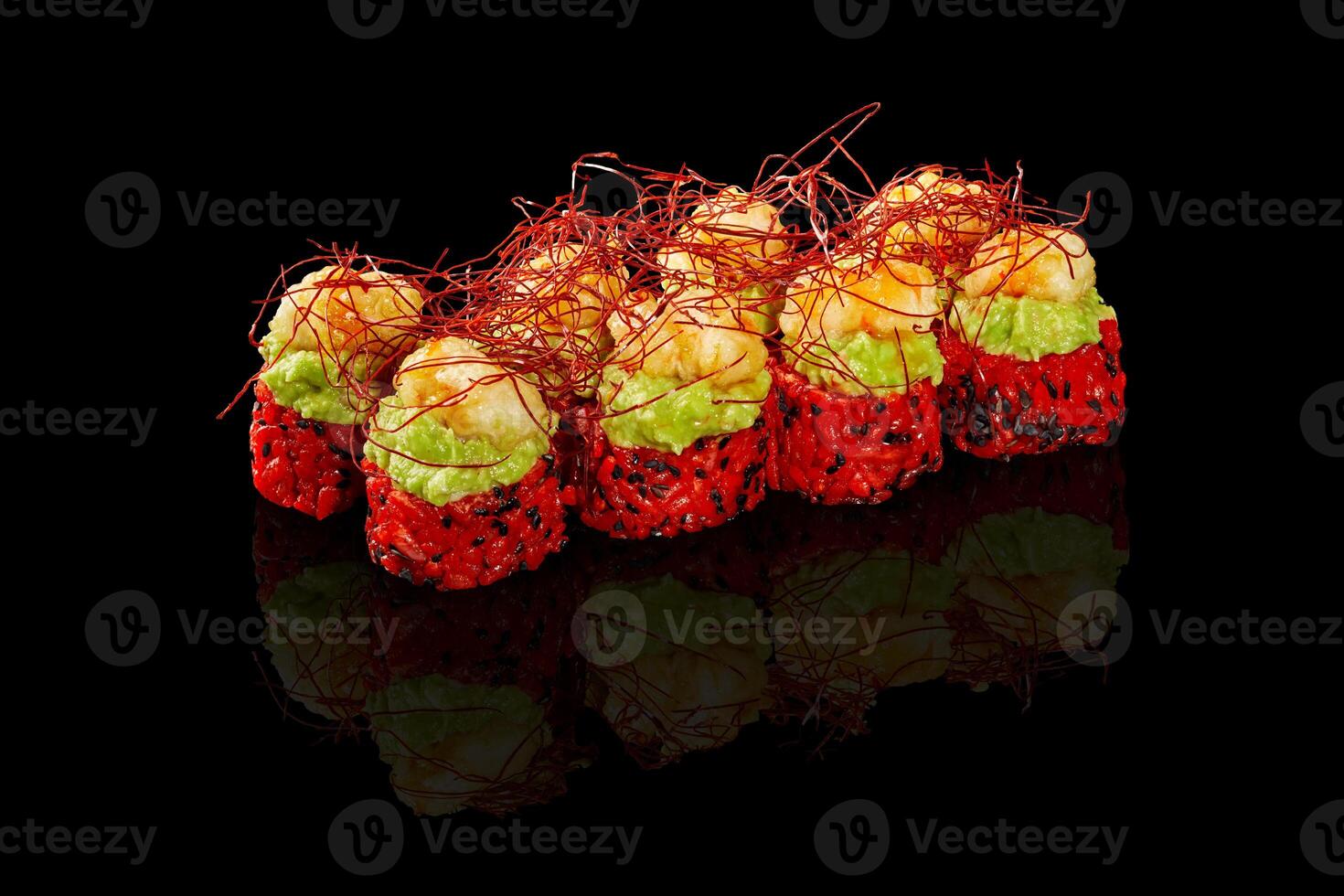 Delicious red sushi rolls topped with shrimp and guacamole with saffron reflecting on black background photo