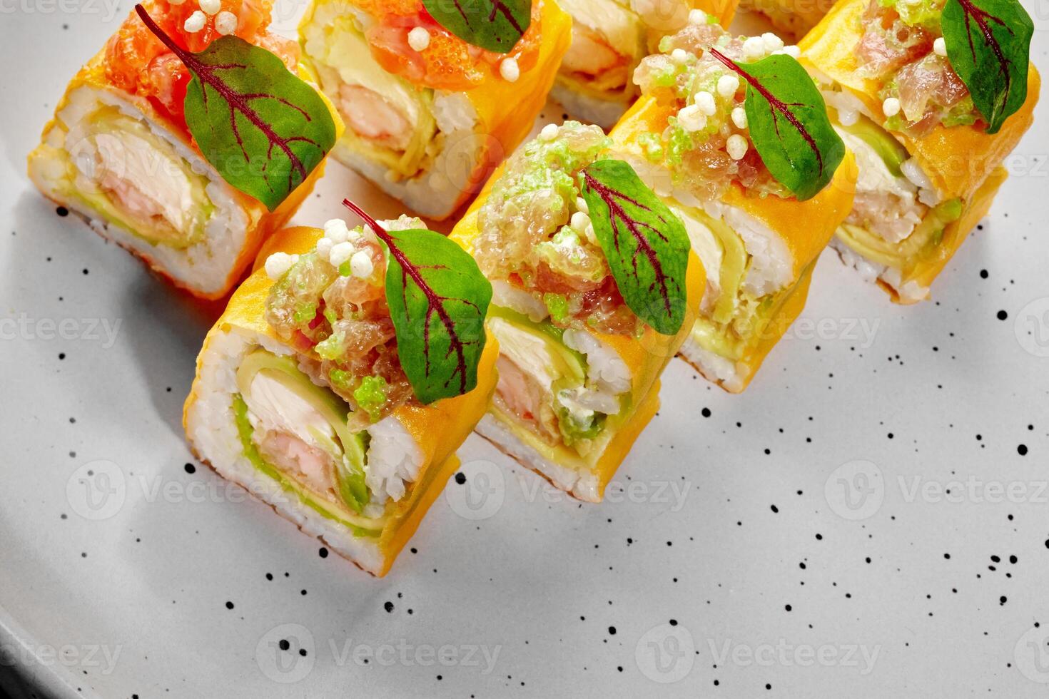 Delicious sushi rolls with omelette, shrimp, avocado, and tobiko on a plate photo