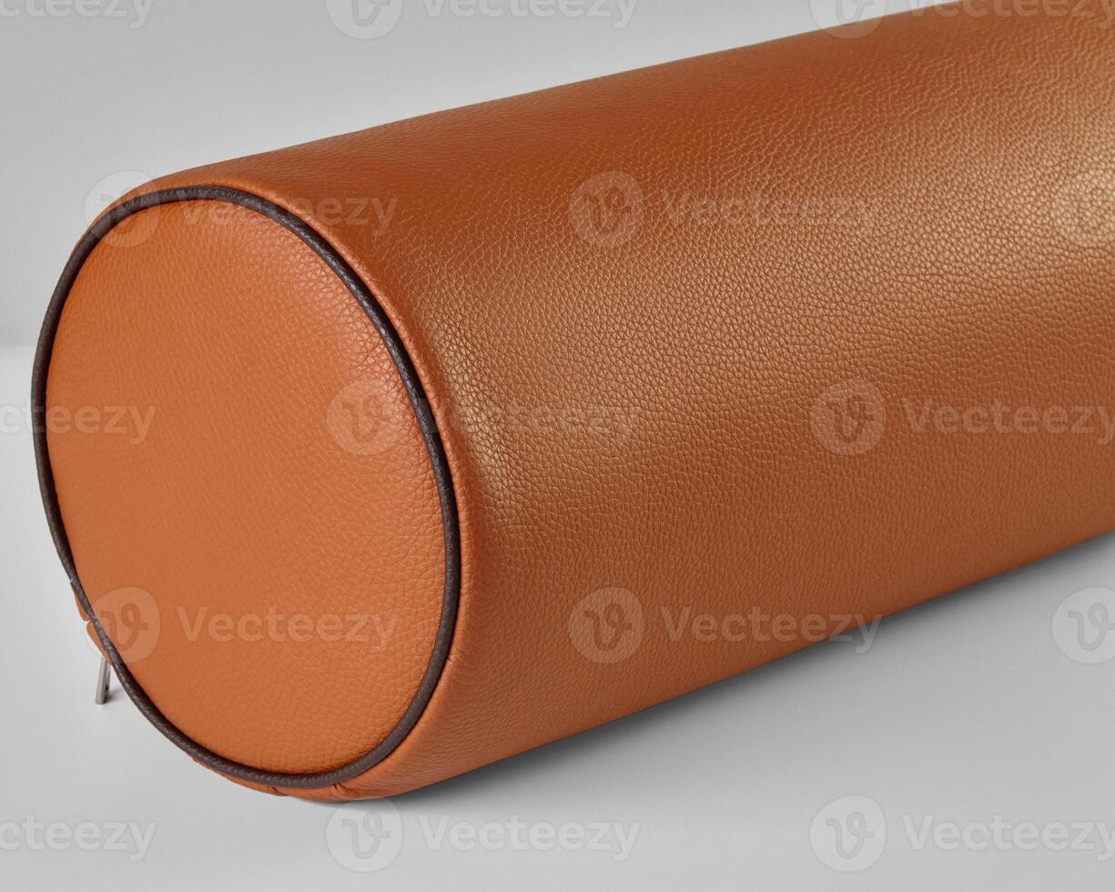 Close-up of a bolster cushion with orange eco-leather upholstery resting on a light gray surface photo