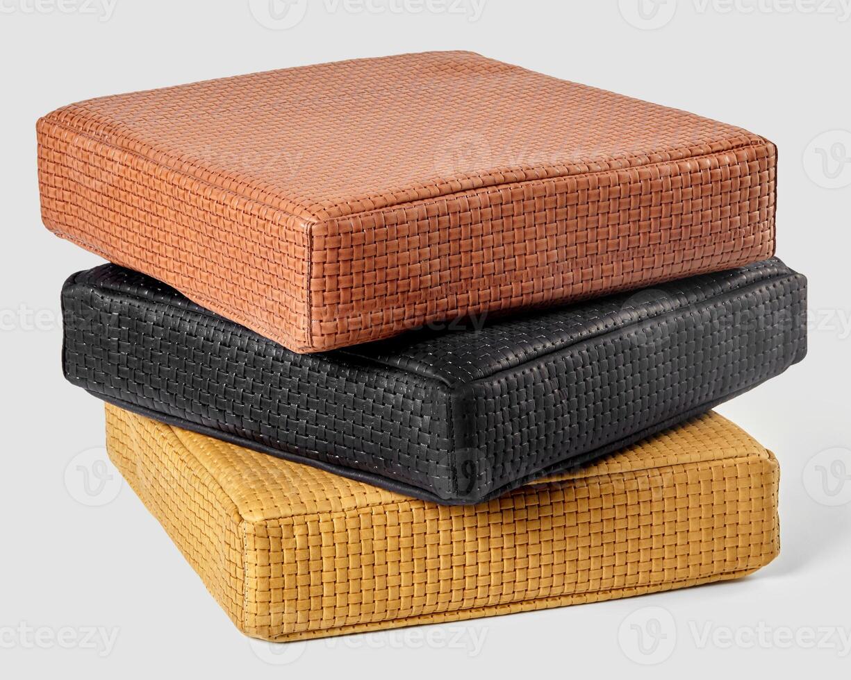 Stack of three square leather cushions showing different warm colors photo