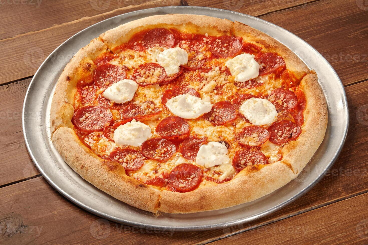 Delicious pepperoni pizza with creamy ricotta and grated parmesan cheese on wooden table photo