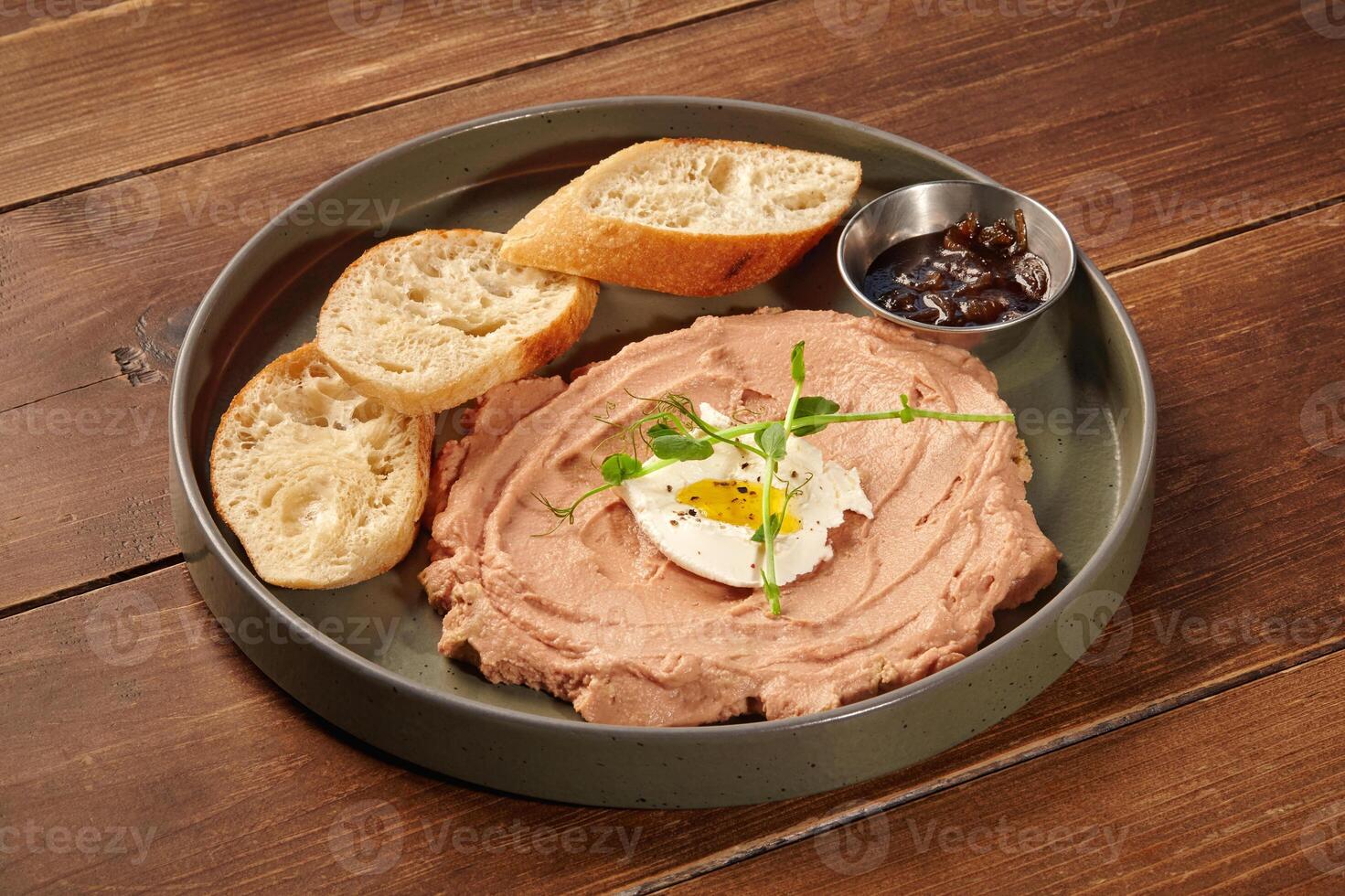 Chicken liver pate with quail egg, onion marmalade and toasted bread on wooden table photo