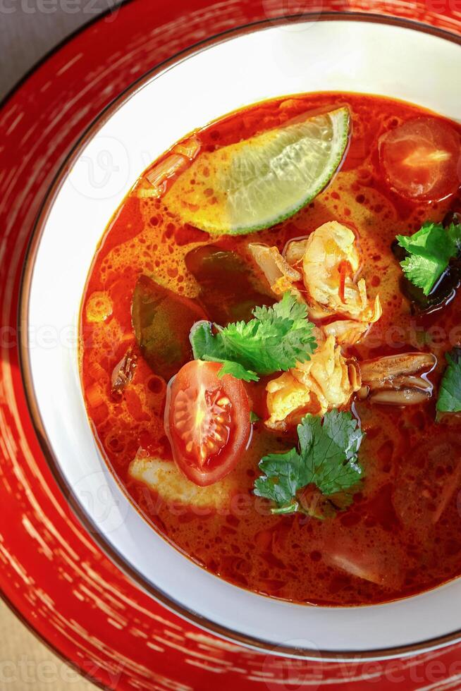 Spicy tom yum soup with shrimp, lime, and cilantro in a bowl photo