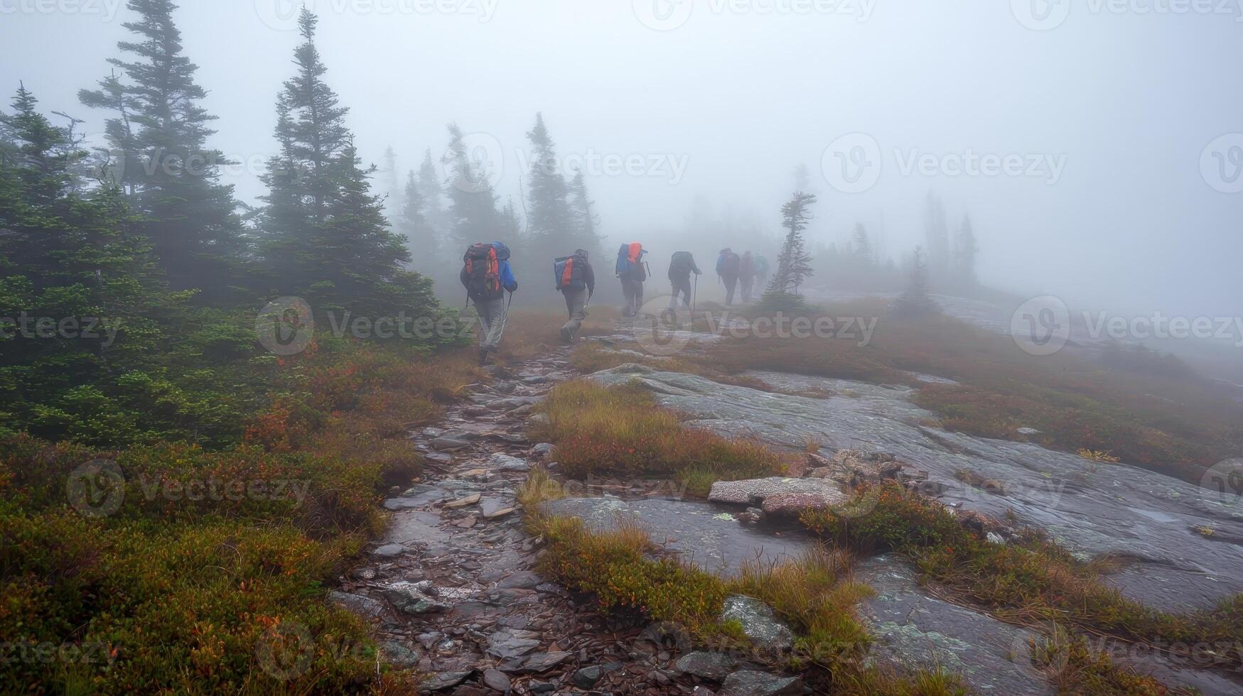 Group of hikers in reflective gear trek along a rocky path through dense fog in the mountains photo