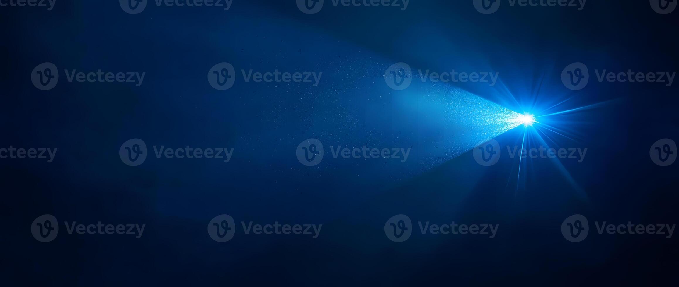 A bright blue spotlight shines brilliantly against the inky backdrop, illuminating specks of suspended particles photo
