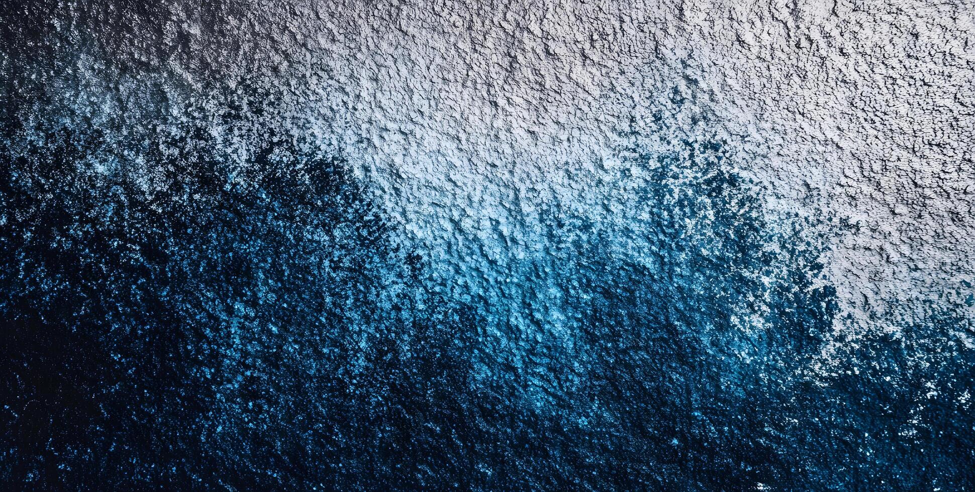 Aerial perspective shows a textured surface transitioning from deep blue to lighter gray photo