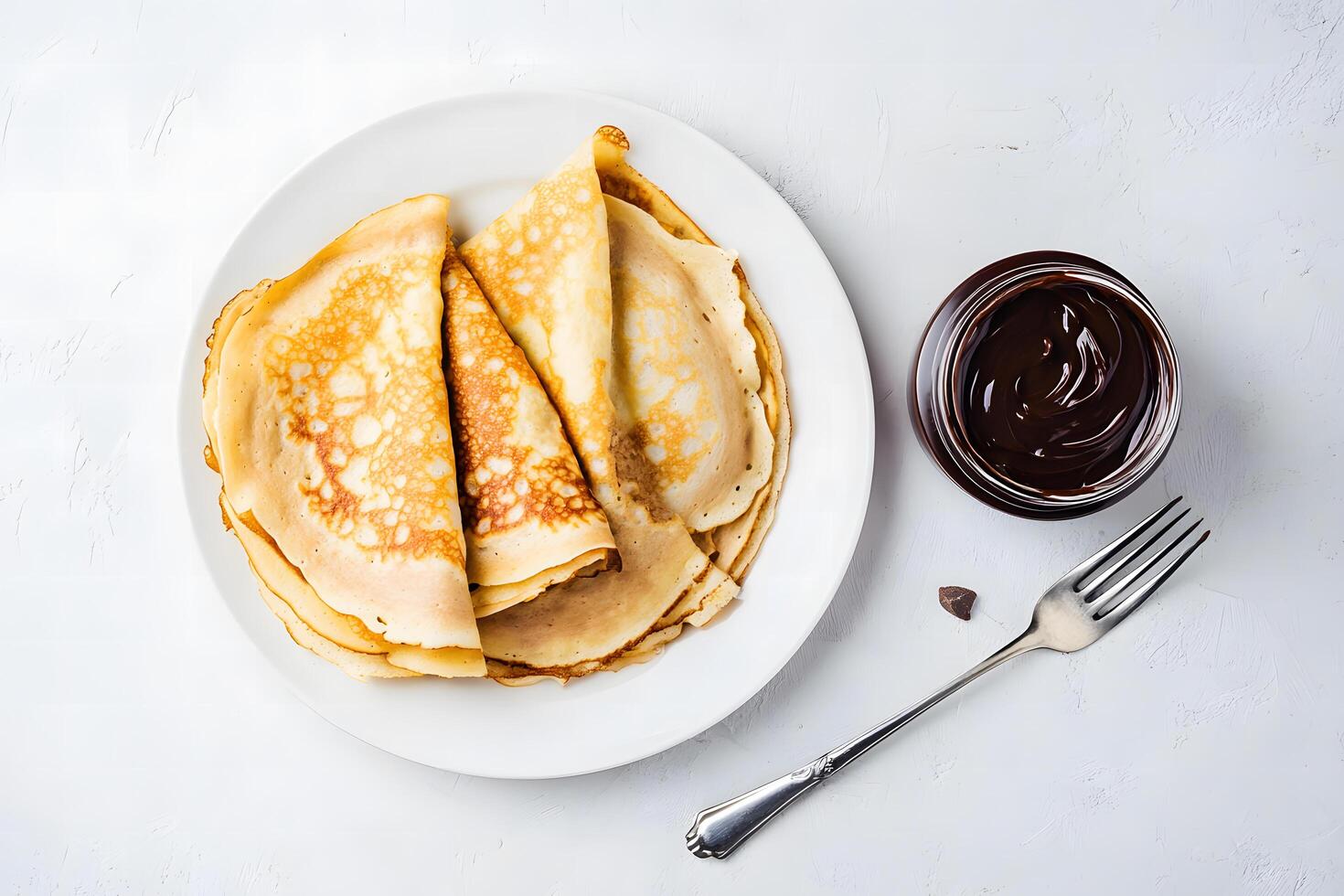 Crispy golden crepes on white plate are ready to be served with rich chocolate photo