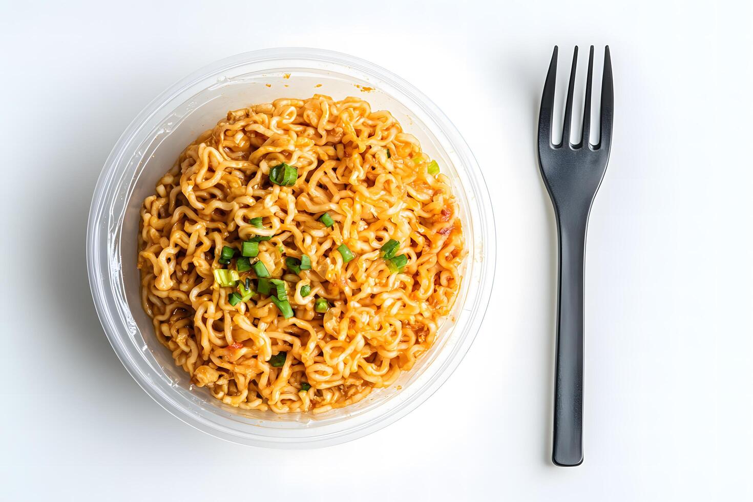 Overhead shot shows ramen noodles with scallions beside a fork on white surface photo