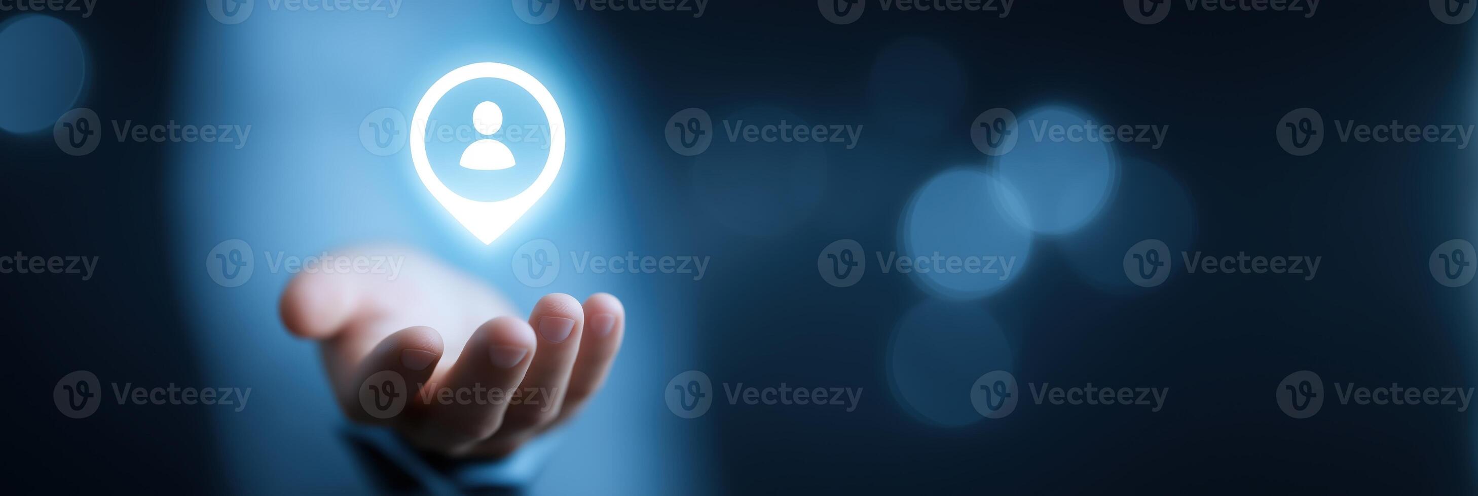 A hand holding a glowing icon of a person on a dark background photo
