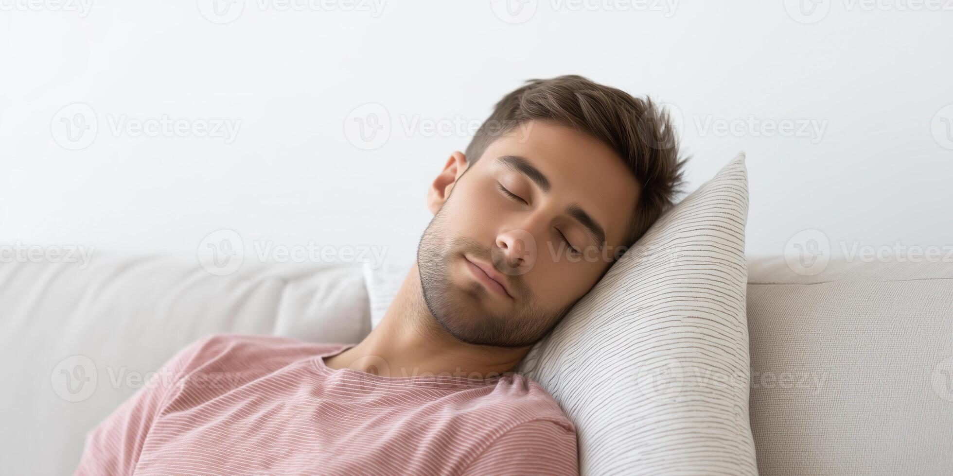 Young man with brown hair is peacefully sleeping on a couch, resting his head on a soft pillow, creating a serene and tranquil atmosphere in a cozy living space photo
