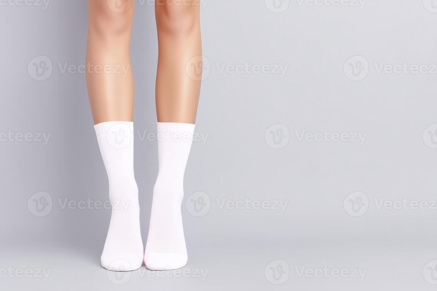 Female legs wearing white socks standing on a smooth gray surface with soft lighting creating a calm and minimalist atmosphere photo