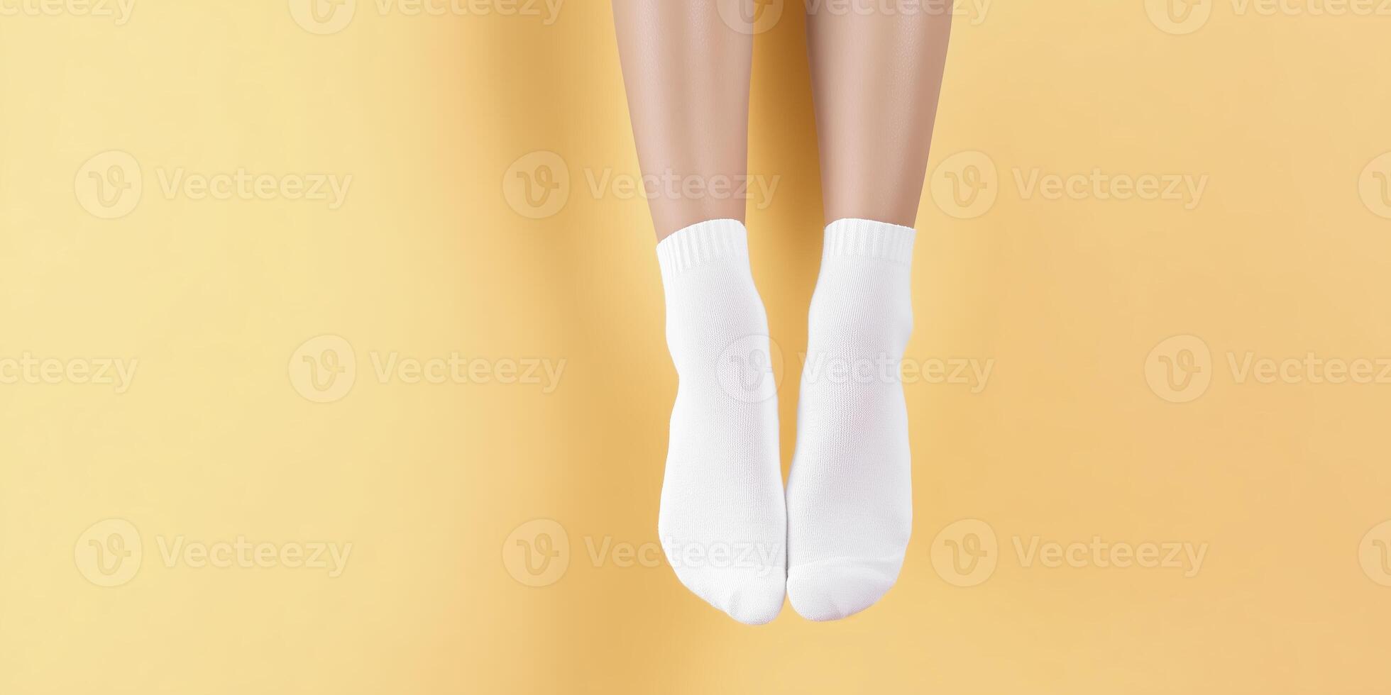 White socks on feet are suspended against a bright yellow background, showcasing a minimalist design that emphasizes comfort and casual style in everyday wear photo
