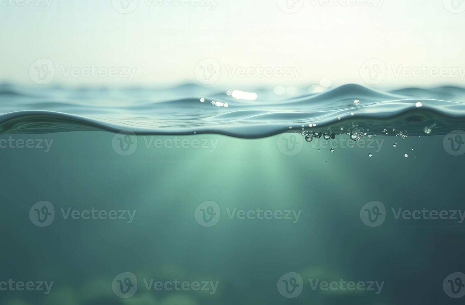 Half-underwater split view of turquoise ocean water with air bubbles and sunbeams photo