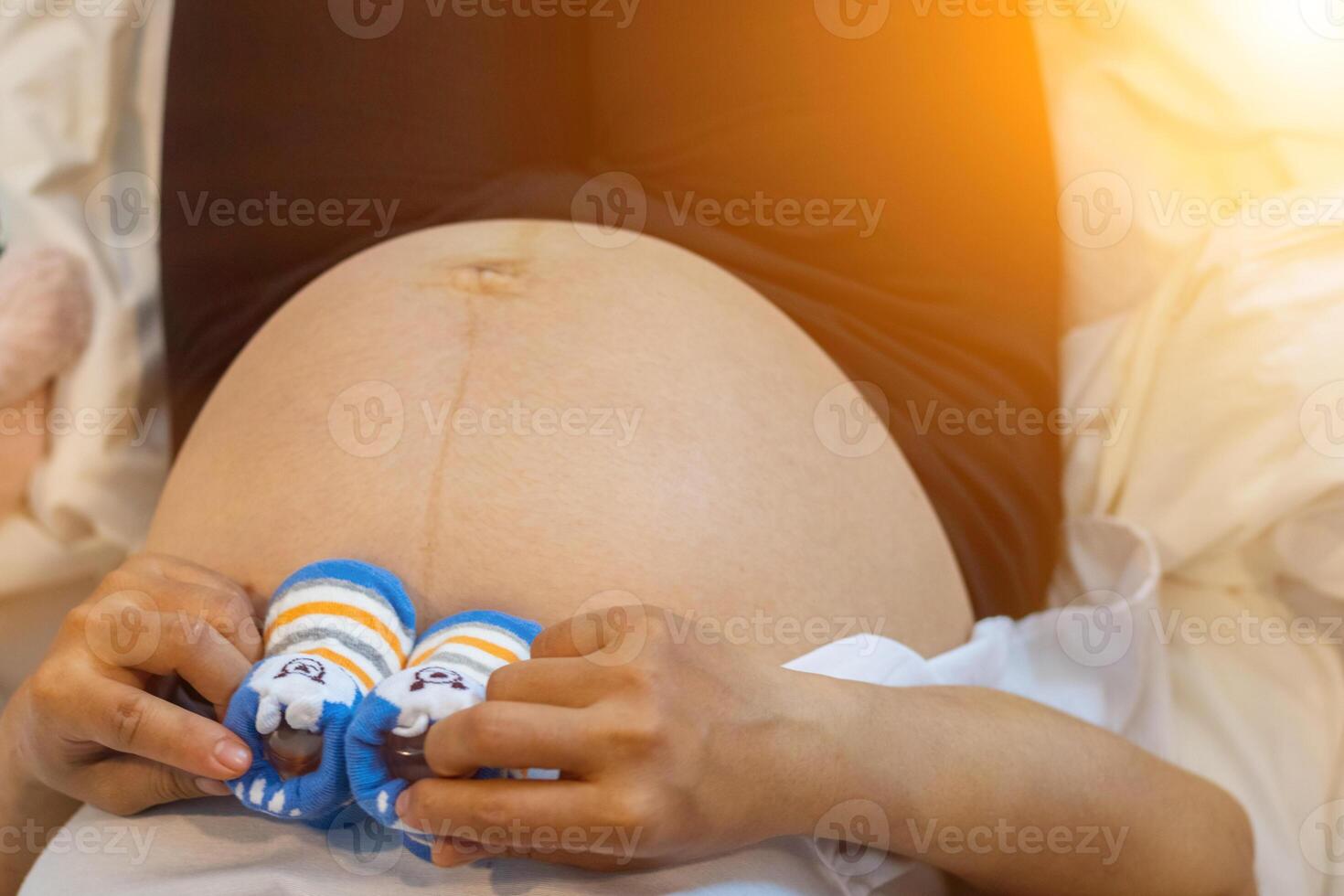 A pregnant woman holding her feet in blue shoes photo